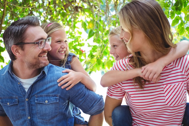 Genitori sorridenti che danno sulle spalle ai bambini