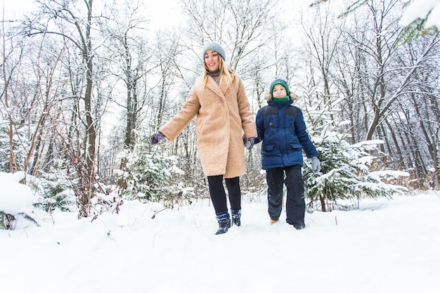 Genitorialità, divertimento e concetto di stagione - Felice madre e figlio che si divertono e giocano con la neve nella foresta invernale.