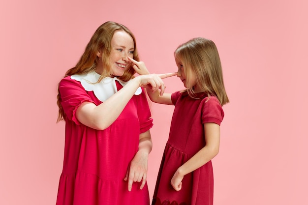 Genitorialità giocosa, bella madre felice che gioca con il suo piccolo daubert contro lo studio rosa