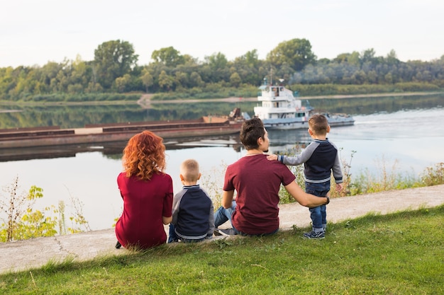 Genitorialità, infanzia e concetto di natura. Famiglia seduta sul terreno verde e guardando in piccolo