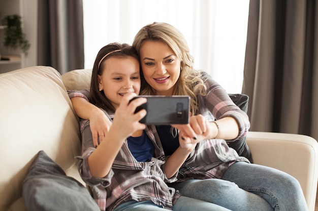 Genitorialità moderna della giovane madre con la sua piccola figlia che utilizza lo smartphone.