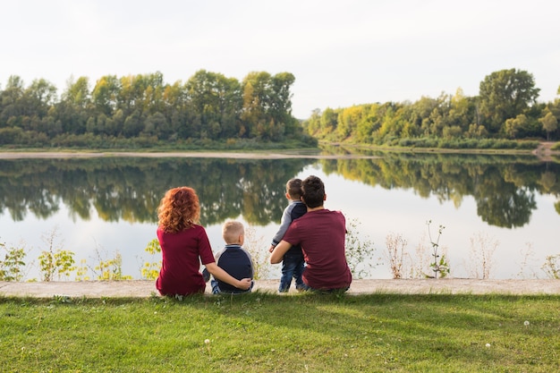 Genitorialità, natura, concetto di persone. famiglia con due figli seduti vicino al lago