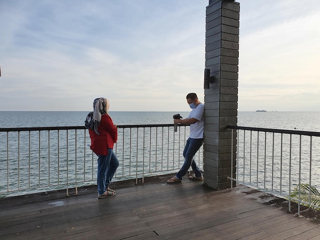 Gennaio 2021 Balikpapan Indonesia Fotografo che scatta un ritratto di una donna sul mare