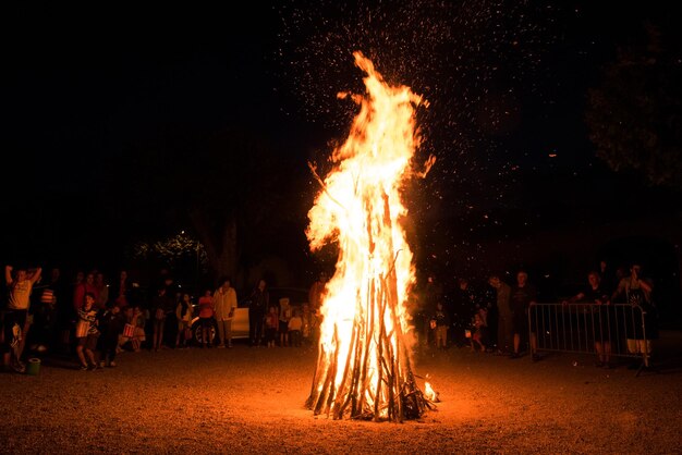 Gente accanto a un falò a terra di notte