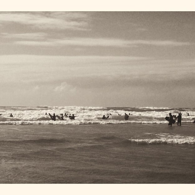 Gente che fa surf in mare contro un cielo nuvoloso