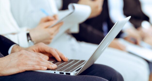 Gente d'affari che lavora in una riunione o in una conferenza, close-up delle mani. Gruppo di uomini d'affare e donne sconosciute in un moderno ufficio bianco. Lavoro di squadra o concetto di coaching.