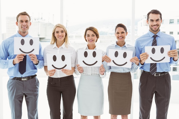 Gente di affari che tiene le emoticon felici in ufficio