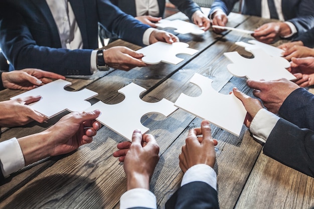 Gente di affari e puzzle sulla tavola di legno, concetto di lavoro di squadra