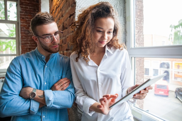 Gente di affari felice che lavora al tablet in un ufficio moderno. Donna d'affari sorridente che mostra le modifiche apportate alla presentazione