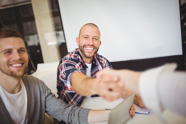 Gente di affari sorridente che stringe le mani in ufficio