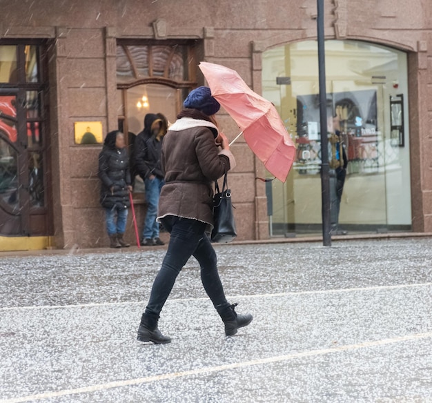 Gente di città occupata che va lungo la via nel giorno nevoso di inverno. Sfocatura da movimento intenzionale. Immagine sfocata