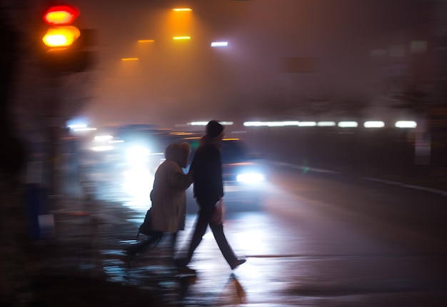 Gente di strada occupata della città sulle strisce pedonali di notte. Situazione pericolosa. Sfocatura da movimento intenzionale