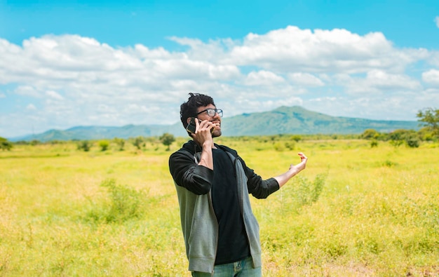 Gente felice che parla al cellulare nel campo Uomo che chiama al telefono nel campo Un uomo in campagna che parla al telefono Uomo sorridente che chiama al telefono sul campo