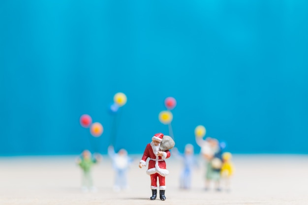 Gente in miniatura: Babbo Natale e bambini che tengono il pallone