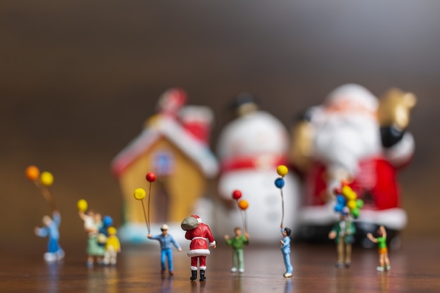 Gente in miniatura: Babbo Natale e bambini che tengono il pallone