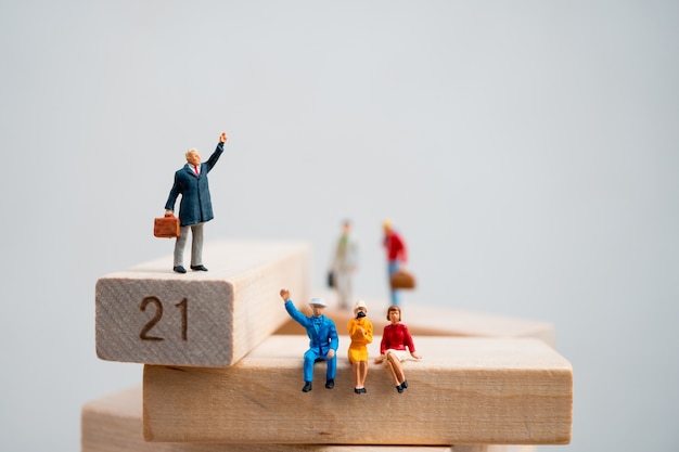 Gente miniatura, gruppo di affari che sta sul blocco di legno facendo uso come concetto di affari
