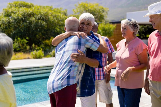 Gente senior felice e diversa che fa festa e si abbraccia in giardino. Stile di vita senior, amicizia e relax, pensione, inalterato.