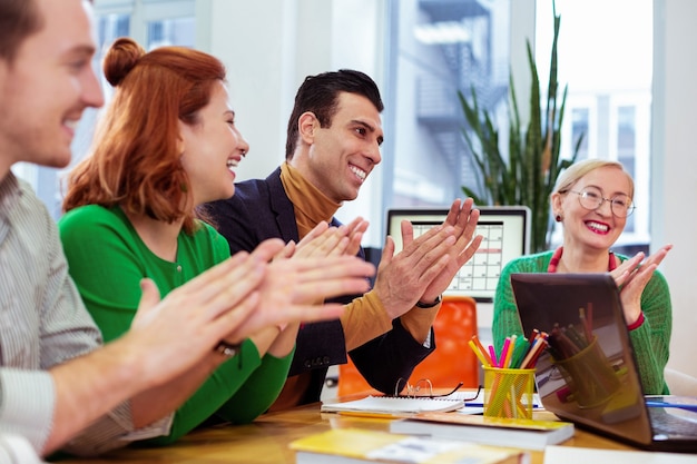 Gente simpatica e gioiosa che applaude mentre sostiene il collega