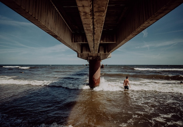 Gente sulla spiaggia sul ponte contro il cielo