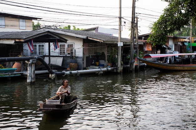 Gente tailandese delle donne che rema e guida la barca di legno nel piccolo canale al sottodistretto di Bang Mod del distretto di Thung Khru il 9 dicembre 2017 a Bangkok Tailandia