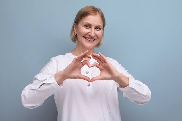 Gentile donna matura bionda piacevole con viso pulito all'età della menopausa sullo sfondo dello studio