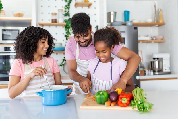 Gentili genitori africani che insegnano alla loro adorabile figlia come cucinare cibo sano in uno spazio libero