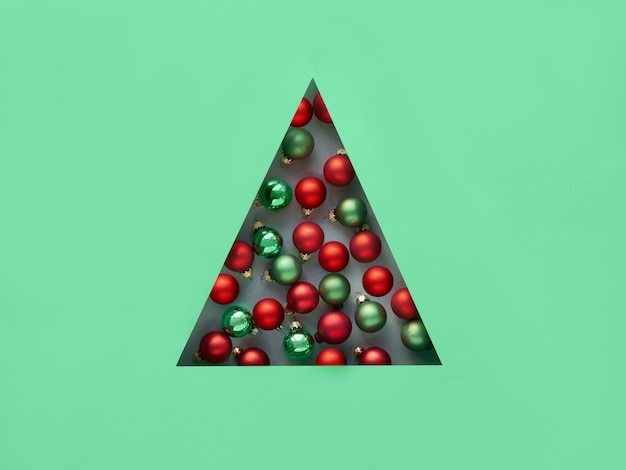 Geometrico creativo piatto natalizio giaceva in neo menta e colori rossi. Bagattelle di Natale in foro triangolare di carta a forma triangolare di albero di Natale.