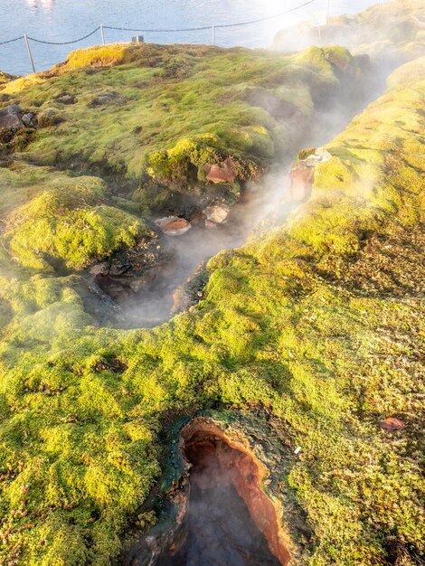 Geotermico della piscina termale con montagne circostanti e punti di eruzione nella città di Fludir in Islanda