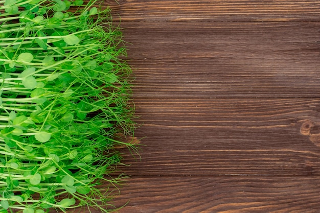 Germogli di giovani piselli microverdi su un tavolo di legno Concetto di cibo sano e vegano Piantine in crescita Posto per un'iscrizione Vista dall'alto