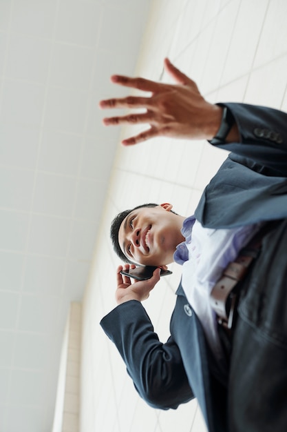 Gesticolano uomo d'affari che chiama sul telefono