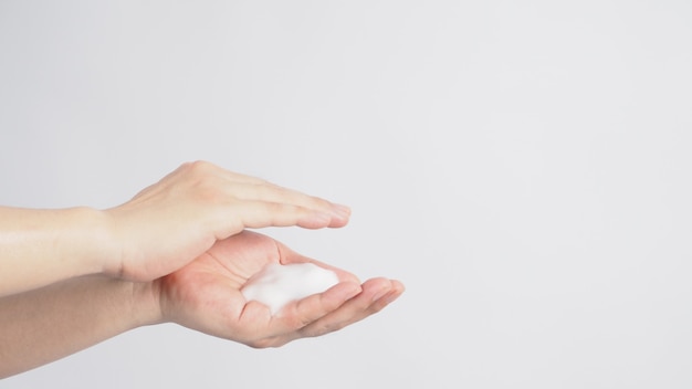 Gesto di lavaggio delle mani con sapone per le mani schiumogeno su sfondo bianco.