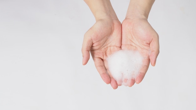 Gesto di lavaggio delle mani con sapone per le mani schiumogeno su sfondo bianco.