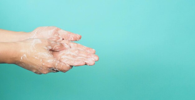 Gesto di lavaggio delle mani con sapone schiumogeno per le mani su sfondo verde e blu Tiffany