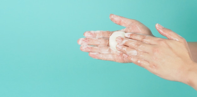 Gesto di lavaggio delle mani con saponetta e bolla su sfondo verde menta o Tiffany Blue.