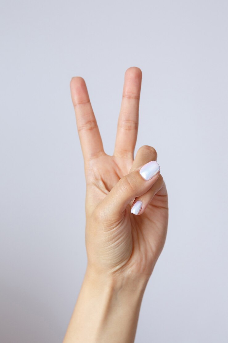Gesto e segno, mano femminile su bianco. Dita che mostrano pace o vittoria