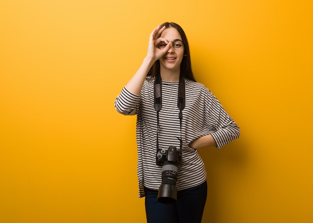 Gesto giusto facente sicuro della giovane donna del fotografo sull'occhio