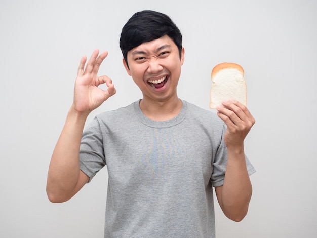 Gesto positivo del giovane ok tenendo il pane in mano isolato