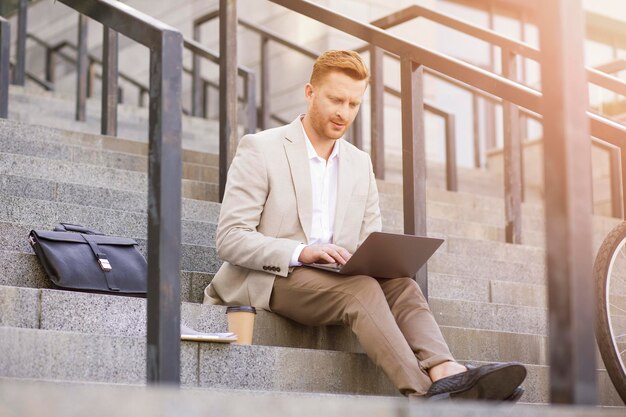 Gestore abile ed elegante che utilizza un laptop e tiene riunioni online mentre è concentrato