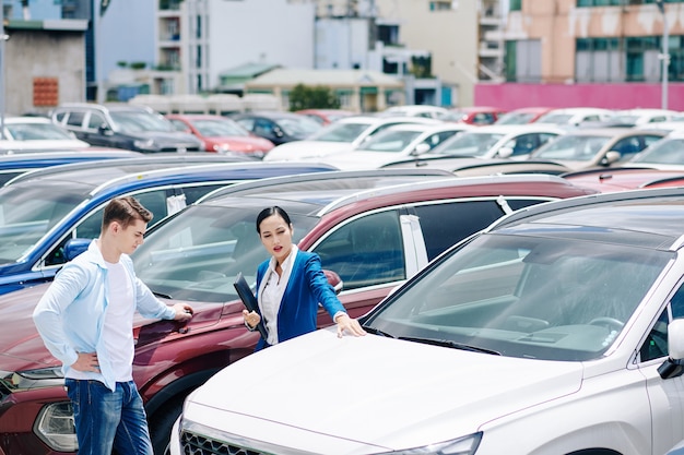 Gestore di concessionaria femminile che aiuta il cliente a scegliere una nuova auto