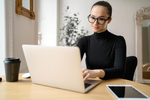 Gestore freelance navigare in Internet Una donna che lavora in un ufficio utilizza un laptop Scrive una lettera