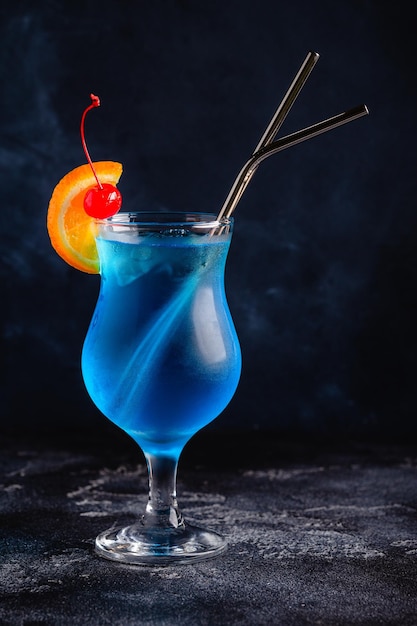 gGass di cocktail laguna blu decorato con arancia e ciliegia sullo sfondo del bancone bar festivo