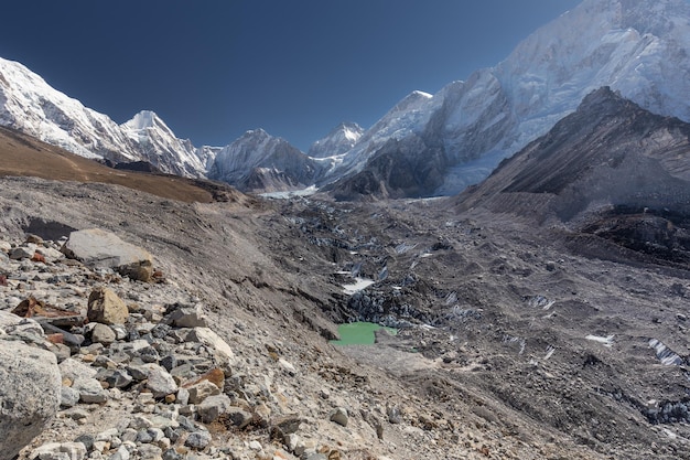 Ghiacciaio del Khumbu coperto di terra e pietre tra le montagne di neve sotto il cielo limpido Nepal Himalaya