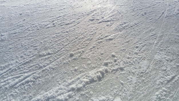 Ghiaccio striato con la punta dei pattini Pattinaggio artistico sul ghiaccio La superficie della pista di pattinaggio dopo l'esercizio dei pattinatori Raggio di sole sul ghiaccio umido primaverile Neve e acqua ghiacciata