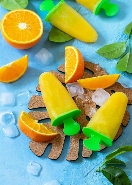 Ghiaccioli fatti in casa con succo d'arancia ghiaccio alla frutta su pietra blu o sfondo di ardesia Spazio di copia