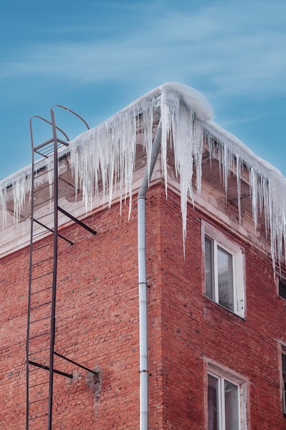 Ghiaccioli grandi e taglienti sul tetto Ghiaccioli pericolosi sulla facciata dell'edificio