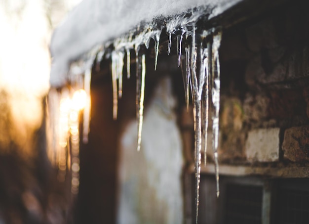 Ghiaccioli invernali appesi al tramonto sul tetto