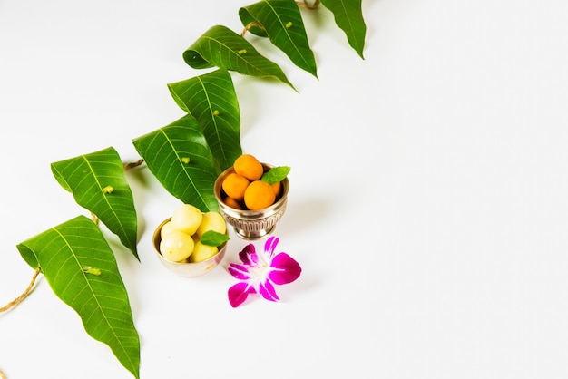 Ghirlanda di foglie di mango con pedha dolce indiano e fiori di orchidea.
