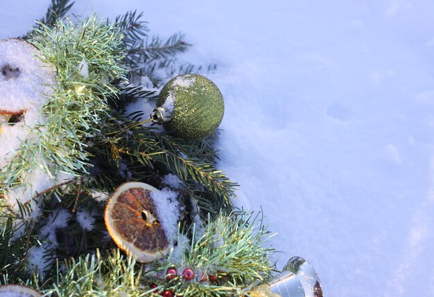 Ghirlanda di Natale decorata con fette d'arancia secche e palline colorate su sfondo bianco di neve.