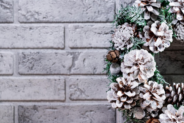 Ghirlanda di Natale fatta di rami di abete e coni naturali Sullo sfondo di un muro di mattoni grigi Capodanno e vacanze invernali Decorazioni natalizie Primo piano