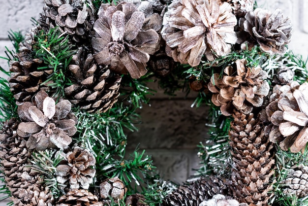 Ghirlanda di Natale fatta di rami di abete e coni naturali Sullo sfondo di un muro di mattoni grigi Capodanno e vacanze invernali Decorazioni natalizie Primo piano